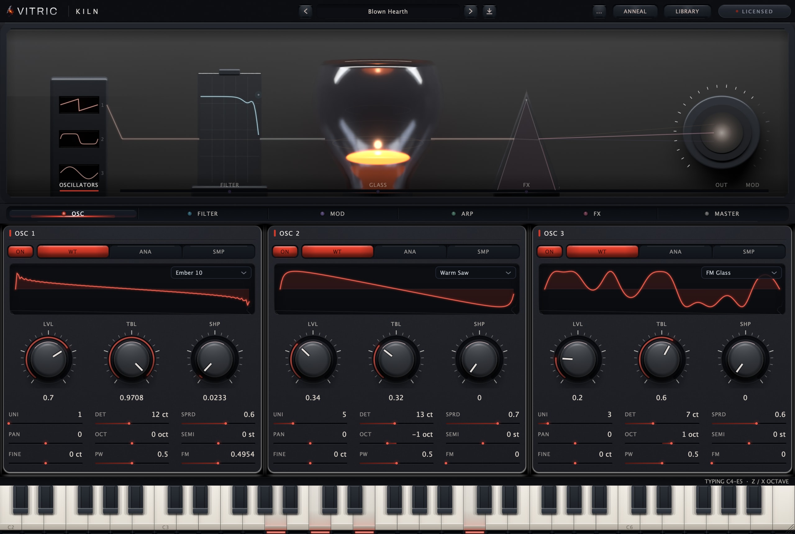 Kiln Synthesizer 0.2.0, licensed, on the factory preset Blown Hearth: the furnace stage with the filter slab and the lit glass vessel, three oscillator slots running Ember 10, Warm Saw and FM Glass under the section rail, and the keybed across the foot of the plate.