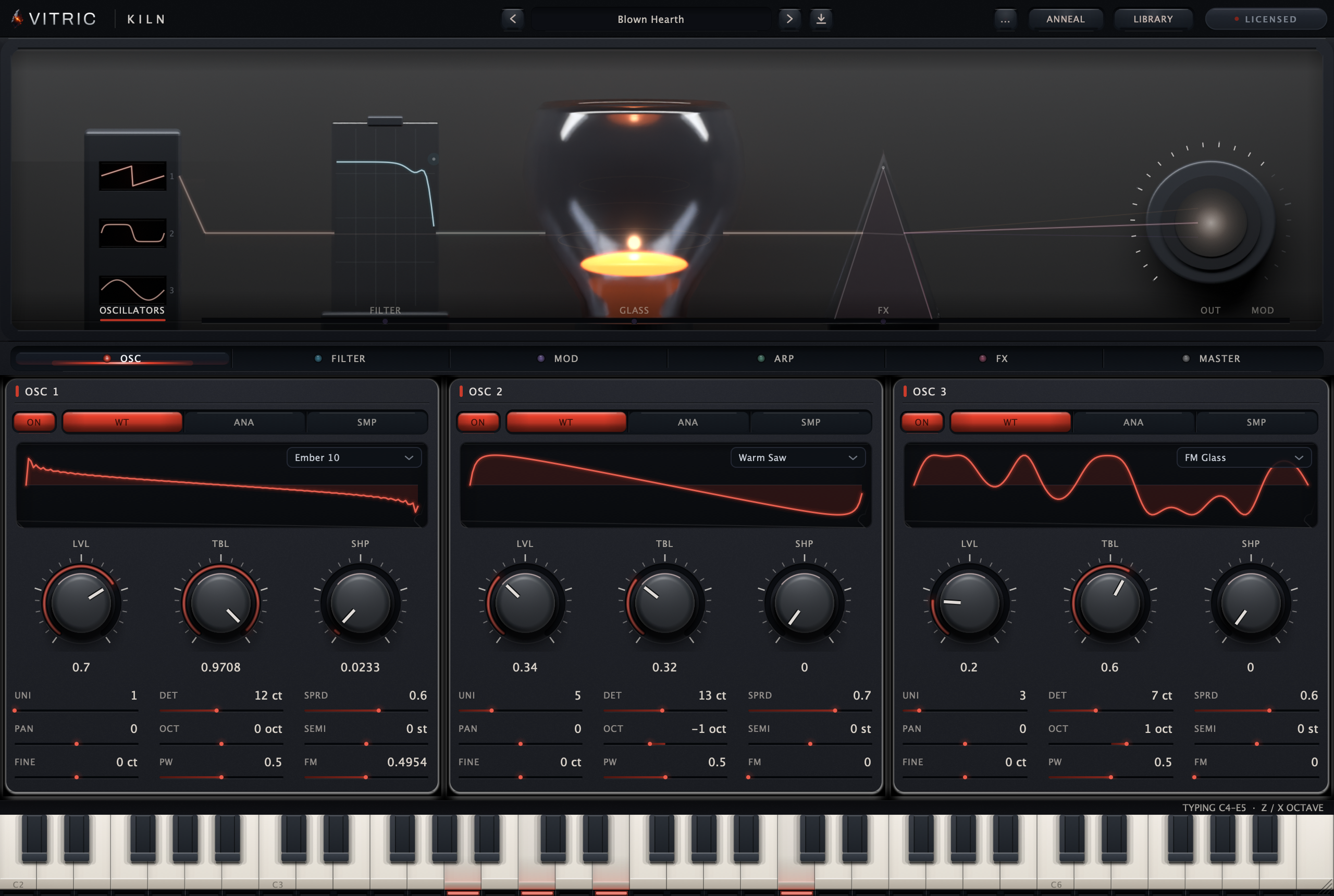 Kiln Synthesizer 0.2.0, licensed, on the factory preset Blown Hearth: the furnace stage with the filter slab and the lit glass vessel, three oscillator slots running Ember 10, Warm Saw and FM Glass under the section rail, and the keybed across the foot of the plate.
